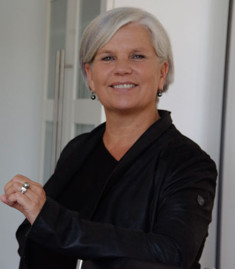 Eine Frau blickt lächelnd in die Kamera.