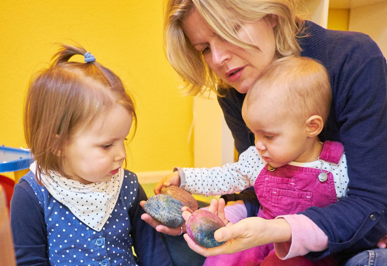 Erzieherin zeigt Kinder bunte Sterne